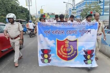 "ব্যানার ও লিফলেট হাতে নিয়ে রোড সেফটি মিছিল করছে স্থানীয় স্বেচ্ছাসেবকরা ও পুলিশ কর্মীরা।"